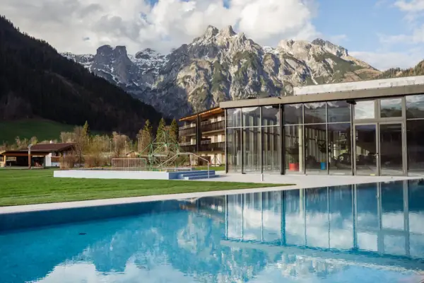 Ein Pool mit dem Badehaus Werfenweng im Hintergrund.