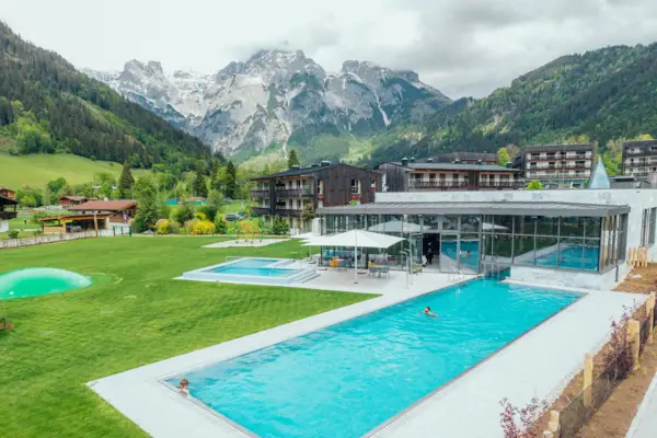 Außenpool Schwimmbecken mit einem Gebäude und Bergen im Hintergrund.