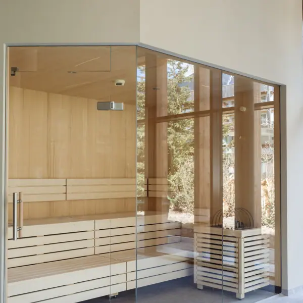 Glastür einer Sauna mit Holzwänden und Holzboden.