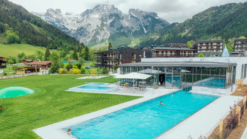 Schwimmbecken mit einem Gebäude und Bergen im Hintergrund