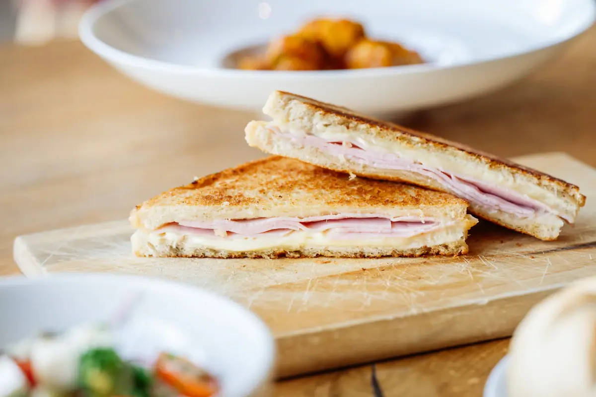 Ein halbiertes Sandwich auf einem Holzbrett aus dem Bistro im Badehaus Werfenweng..